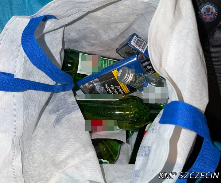 Biała torba wypełniona szklanymi butelkami z alkoholem oraz papierosami.