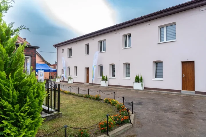budynek w Warnicach po termomodernizacji, uwagę zwraca jasna, nowa elewacja, wymienione okna i drzwi