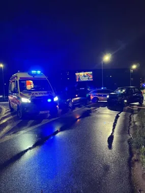 Nocna akcja służb ratunkowych i policji na mokrej drodze po zderzeniu dwóch samochodów osobowych.