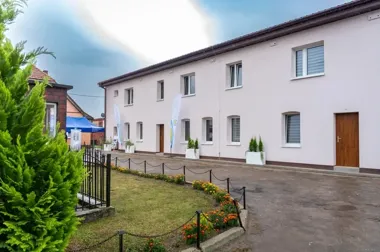budynek w Warnicach po termomodernizacji, uwagę zwraca jasna, nowa elewacja, wymienione okna i drzwi
