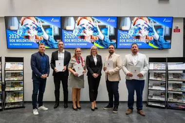 Sześć osób pozuje do fotografii w pomieszczeniu z trzema ekranami wyświetlającymi hasło „2026 Rok Wolontariatu na Pomorzu Zachodnim”.